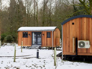 Belmont, Chorley, Lancashire, İngiltere, 01-11-2025: Çıplak ağaçlarla kaplı bir kış manzarasında ahşap glamping kulübeleri.
