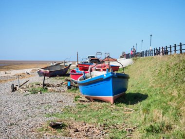 Renkli balıkçı tekneleri berrak bir gökyüzünün altında huzurlu çakıllı bir sahilde dinleniyor. Lytham, Lancsashire.