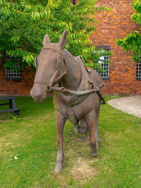 Tuğla binanın yakınındaki çimenlikte bronz at heykeli.