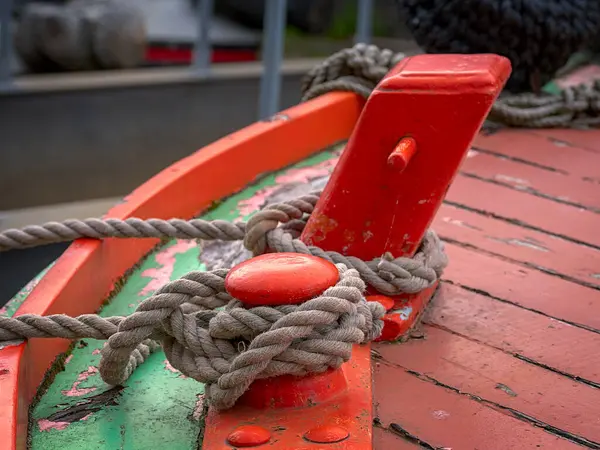 Kırmızı bir kayığa bağlanmış bir halatın yakını renkli bir güvertede..