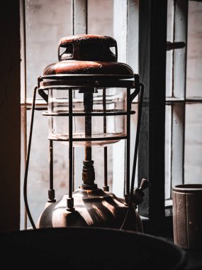 Güneşli bir günde, eski bir petrol feneri, kırsal bir pencerenin yanında gölgeler bırakıyor..