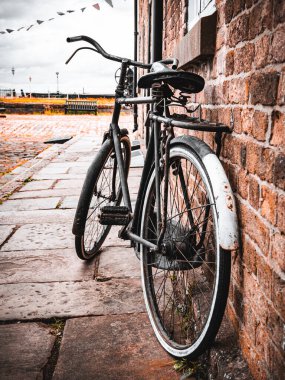 Bir kaldırım taşı sokağında tuğladan duvara yaslanmış eski bir bisiklet..