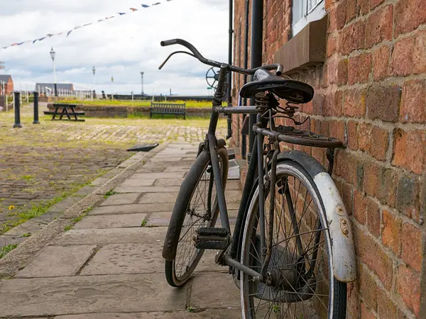 Sakin bir kaldırım taşı caddesinde tuğladan bir duvara yaslanmış klasik bir bisiklet..