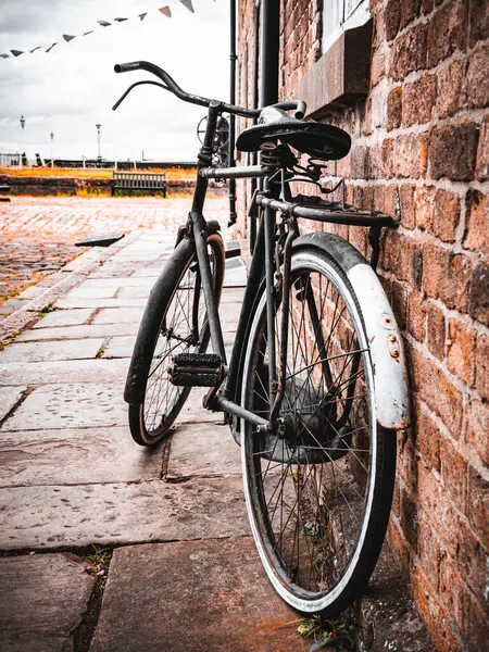 Bir kaldırım taşı sokağında tuğladan duvara yaslanmış eski bir bisiklet..