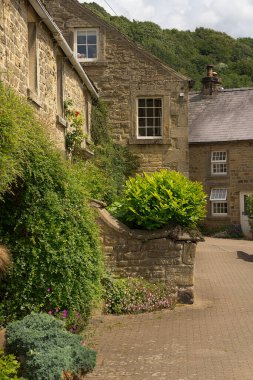 Güneşli bir günde yemyeşil, büyüleyici Derbyshire taştan kulübeleri.