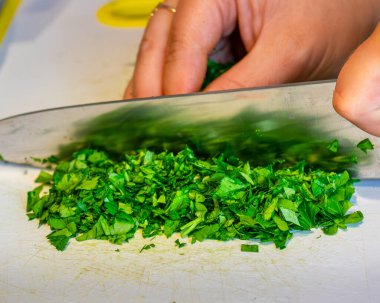 Kadın yeşil soğanı bıçakla kesiyor..