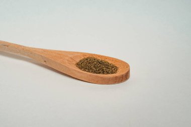 Beyaz zemin üzerinde kenevir tohumları olan ahşap kepçe, üst görünüm.