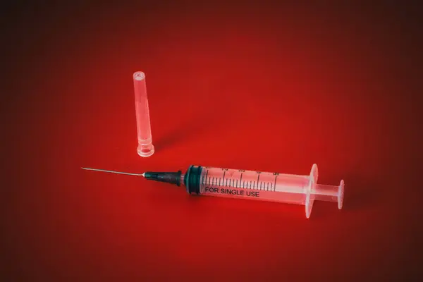 Şırınga ve iğne kırmızı arkaplanda izole edildi