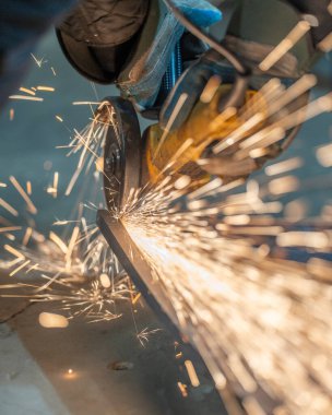 Metal kaynak kıvılcımlarıyla fabrikada çalışan işçiler.