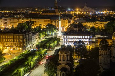 Riga, Letonya - 7 Temmuz 2023: Milda Anıtı Riga ve uzaktaki Ulusal Kütüphane 'nin gece vakti Letonya Oteli' nden bir manzara.