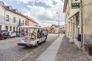 Kuldiga, Letonya - 3 Temmuz 2023: Eski Şehir Meydanı Baznicas caddesi turist minibüsü ve kaldırımlı taş kaldırımlı caddeler.