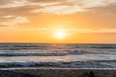 Fırtınadan sonra deniz kıyısında turuncu günbatımı gökyüzü. Parlak, dramatik kırmızı bulutlar..