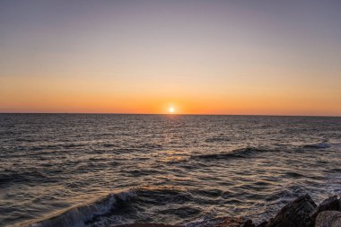Baltık deniz yüzeyinin altında büyük sarı güneşli parlak günbatımı.