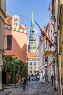 Riga, Letonya - 7 Temmuz 2023: Kramu Iela St. Peters Kilisesi manzaralı küçük tarihi kaldırım.