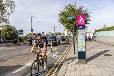 London, UK - September 14, 2023: A super cycle lane, CS8, Cycle Superhighway 8, information board stands tall above the route itself as it passes through Battersea. clipart