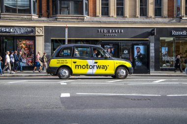 London, UK - September 14, 2023: London Black Yellow Cab Taxi with Motorway Advertisement clipart