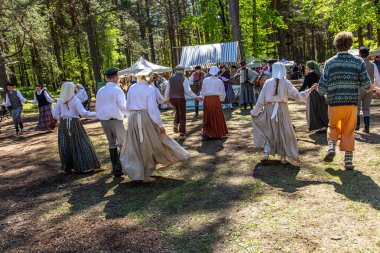 Riga, Letonya - 23 Haziran 2024: Geleneksel kostümlü Letonya halk dansları. Letonya yazı. Ligo tatili için Letonya 'nın sembolü. Letonya 'da yaz ortası.