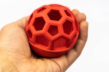 Kırmızı köpek topu şeker dağıtıcısı. İnsan eliyle beslenen hayvan için top oyuncağı beyaz arka planda izole edilmiş.