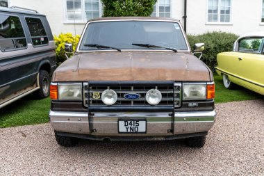 Bristol, UK- August 11, 2024: Front of Old brown 8th Generation 1980s Custom Ford F 150 pickup truck. clipart