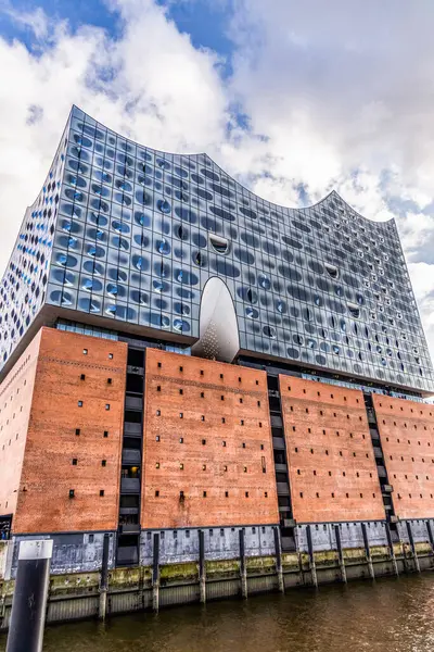 Hamburg 'daki ünlü Elbphilharmonie konser salonu simgesinin göz kamaştırıcı parlak cam cephesi modern, dalga benzeri tasarımını sergiliyor ve gökyüzünü güneş ışığına yansıtıyor..