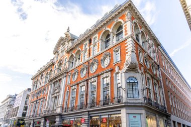 Londra, UK- 19 Eylül 2024: Orta Londra 'daki Tarihi Kırmızı Tuğla Binası Zarif Mimari Cephesi Süslü Detaylar ve Arched Windows. HM ve Uniqlo dükkanları.