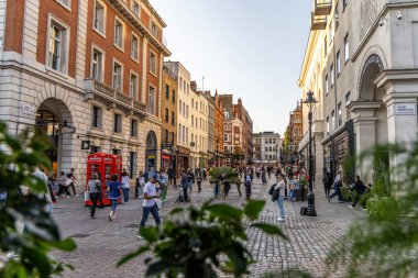 Londra, UK- 19 Eylül 2024: Covent Garden Sokağı Londra 'da Klasik Kırmızı Telefon Kulübeleri, Mimarlar ve Meşgul Yayalar