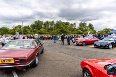 Llandow, Wales - June 30, 2024: A vibrant classic car show with vintage vehicles and enthusiasts socializing at Llandow Circuit. clipart