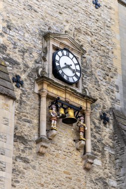 Oxford , UK - June 5, 2024: St Martin's Tower clock, also called Carfax Tower, remains of the Church of St. Martin. It is adorned with two figures called quarter boys who hit the bells. clipart