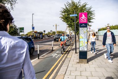 London, UK - September 14, 2023: A super cycle lane, CS8, Cycle Superhighway 8, information board stands tall above the route itself as it passes through Battersea. clipart