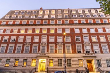 Londra, UK- 19 Eylül 2024: Klasik Londra Mimarisi Aydınlık Pencereli ve Tarihi Büyülü Güzel Tuğla Bina Akşam Manzarası.