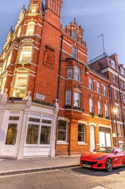 Londra, UK- 19 Eylül 2024: Kızıl Ferrari Portofino Spor Arabası ve Brown Hart Gardens 'taki Klasik Brick Architecture ile Londra Sokak Sahnesi.