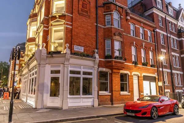 Londra, UK- 19 Eylül 2024: Kızıl Ferrari Portofino Spor Arabası ve Brown Hart Gardens 'taki Klasik Brick Architecture ile Londra Sokak Sahnesi.