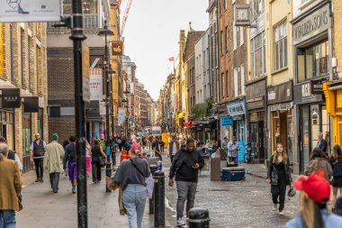 Londra, UK- 19 Eylül 2024: Kalabalık bir şehir ortamında çeşitli insanların dükkanların ve kafelerin önünden geçtiği canlı Soho Londra sokak sahnesi.