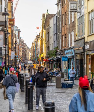 Londra, UK- 19 Eylül 2024: Kalabalık bir şehir ortamında çeşitli insanların dükkanların ve kafelerin önünden geçtiği canlı Soho Londra sokak sahnesi.