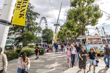 Londra, UK- 6 Ağustos 2023: Queens Walk gezinti güvertesinde yayalar. Thames Nehri Southbank yolundan Westminster Köprüsü 'nden Tower Köprüsü' ne kadar turistler ve ziyaretçiler için gezi.