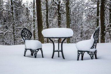Kışın boş restoranlar, boş metal sandalyeler ve karla kaplı masalar..