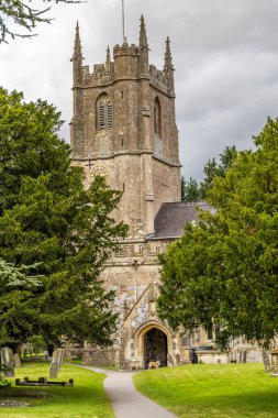 Avebury Kilisesi M.Ö. 1000 yılına dayanır ve Wiltshire 'daki Avebury Malikanesi yakınlarında yer alır. Bir kadın kilisenin yanındaki bankta oturuyor..