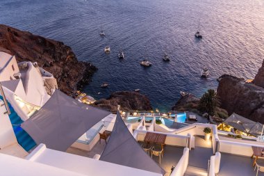 Santorini, Yunanistan - 15 Ekim 2024: Ege Denizi ve Teknelerine Bakan Beyaz Binalarla Santorini 'nin Çarpıcı Gece Manzarası.