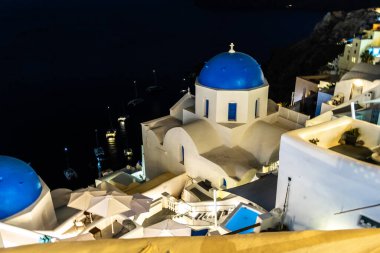 Santorini, Yunanistan - 15 Ekim 2024: Mavi Kubbe Kilisesi ve Ege Denizi 'ndeki Teknelerle Santorini Nightscape.