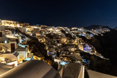 Santorini, Yunanistan - 15 Ekim 2024: Whitewashed Buildings ve Vibrant Lighting ile Santorini 'nin Çarpıcı Gece Sahnesi.