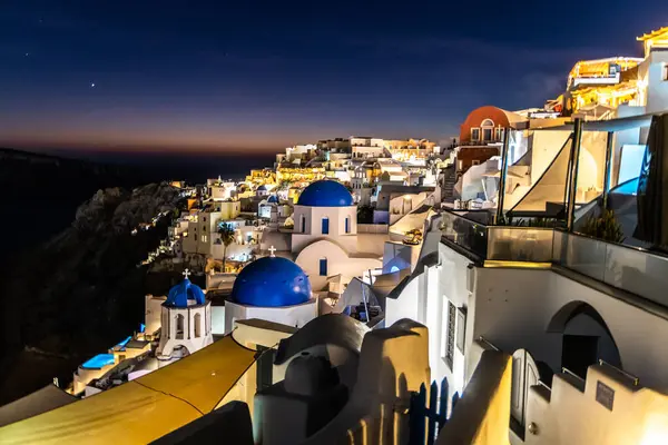 Santorini, Yunanistan - 15 Ekim 2024: Mavi Kubbeli Santorini Gece Manzarası ve Beyaz Yıkanmış Binalar Aydınlandı.