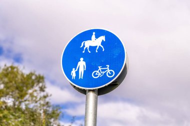 Atların, bisikletlerin ve yayaların kullanımına izin verildiğini gösteren işaretli manzaralı bir kır yolu..