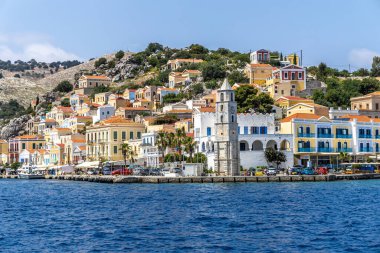 Symi, Yunanistan - 10 Mayıs 2024: Suriye adasındaki Renkli evler ve Saat Kulesi köyü, Dodecanese adaları, Yunanistan.