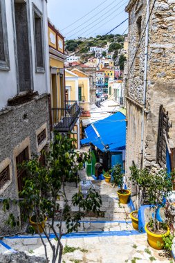 Symi, Yunanistan - 10 Mayıs 2024: Yunanistan 'ın Symi kentinde Bitkilerle Evler ve Çiçekler Arasındaki Mavi Adımlar.