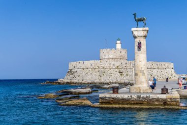 Rodos, Yunanistan - 9 Mayıs 2024: Geyik heykeli ile Mandraki limanı, Heykelin bulunduğu yer ve Aziz Niklas Kalesi. Rodos, Yunanistan. Rodos Heykeli 'nin yerine Hirschkuh heykeli.