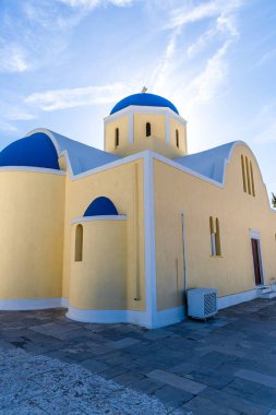 Oia 'daki Agios Georgios Kilisesi' nin belirgin sarı ve mavi kubbesi Ege Denizi 'nin arka planına karşı.