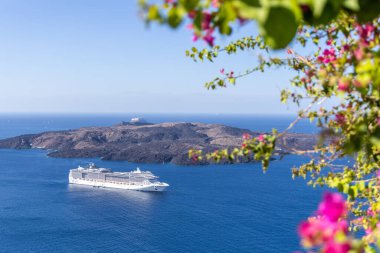 Santorini, Yunanistan - 15 Ekim 2024: Santorini 'nin Azure Waters' ındaki Gezi Gemisi, Çerçeveli Lush Pembe Çiçekler ve Volkanik Adalar.