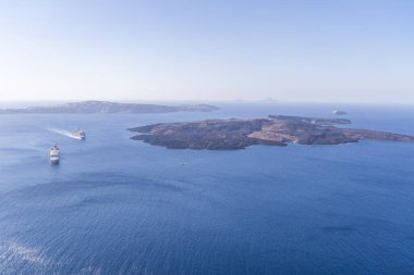 Nea Kameni Adası Volkan Adası. Santorini 'nin Panoramik Deniz Burnu: Açık Gökler Altında Gezici Gemiler ve Volkanik Adalar.