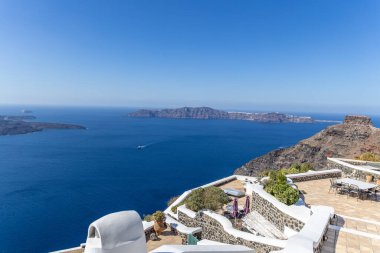 Santorini, Yunanistan - 15 Ekim 2024: Santorini kalderasının açık gökyüzü altında beyazlatılmış evler ve derin mavi deniz manzarası. İkonik Yunan ada manzarası