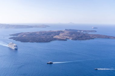 Santorini, Yunanistan - 15 Ekim 2024: Santorini 'nin yanında mavi denizde gemileri ve tekneleri olan volkan adası. Çarpıcı kaldera ve okyanus manzarası